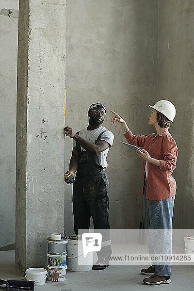 Building contractor giving instructions to coworker at construction site