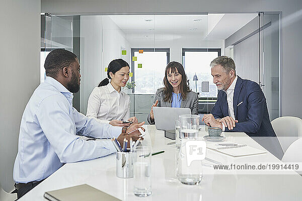 Smiling businessmen and businesswomen having discussion over laptop