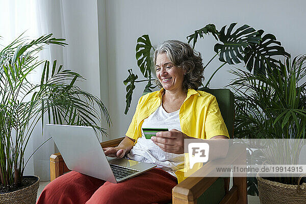 Happy woman doing online shopping using credit card and laptop at home