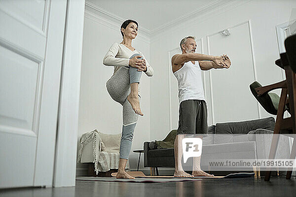 Couple doing stretching exercises in morning at home