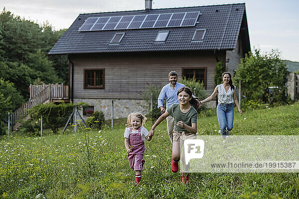 Happy girls running in garden of sustainable family home