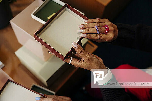 Hands of female entrepreneur holding box lid at office