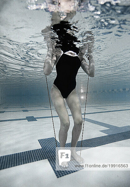 Woman trains using a resistance band in a pool.