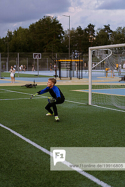 Kids playing soccer  boy goalkeeper catches ball in goal.