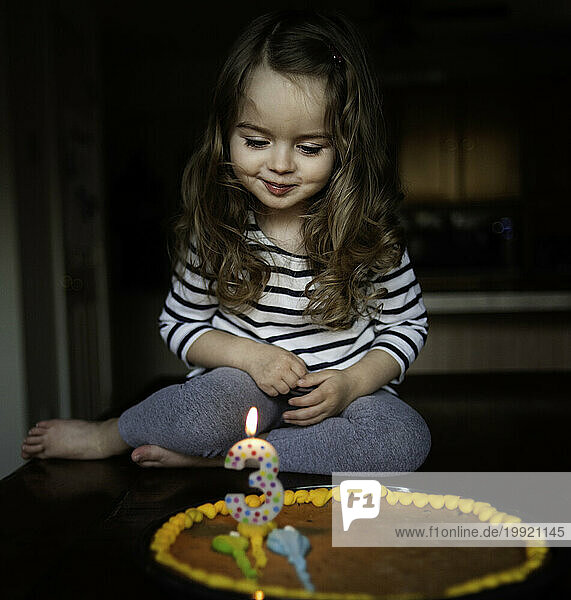 Beautiful little girl making wish on birthday candle