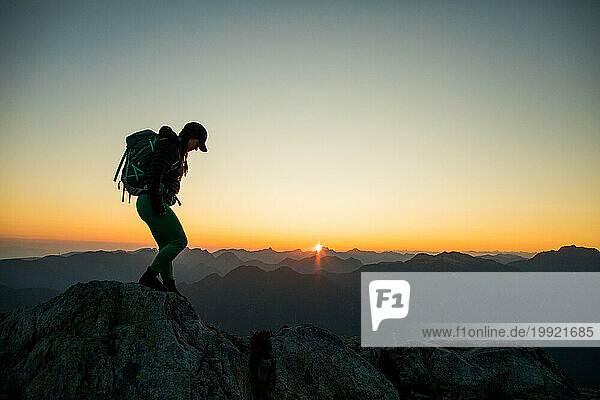 Backpacker hiking mountain ridge at sunrise  alpine start