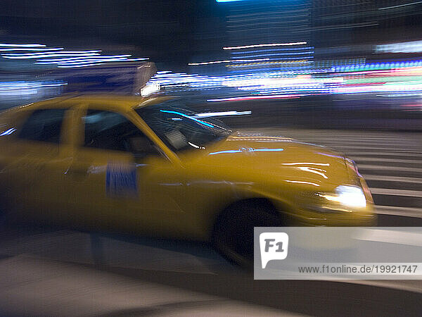 Taxi cabs blur by in the New York  NY night.