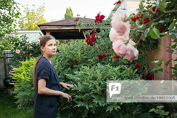 A teenage girl works in a blooming garden