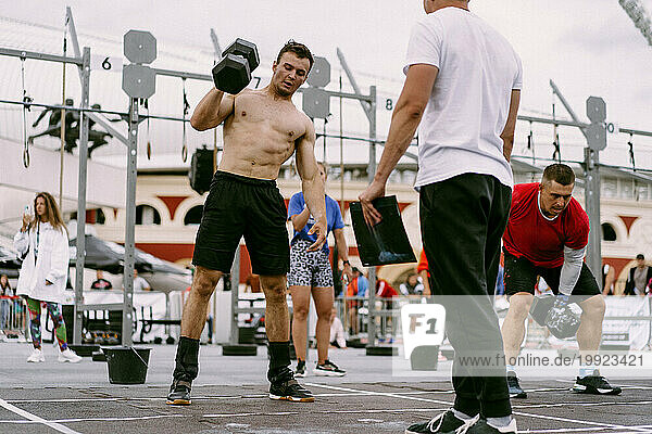 Men's CrossFit competition. A man lifts a dumbbell.
