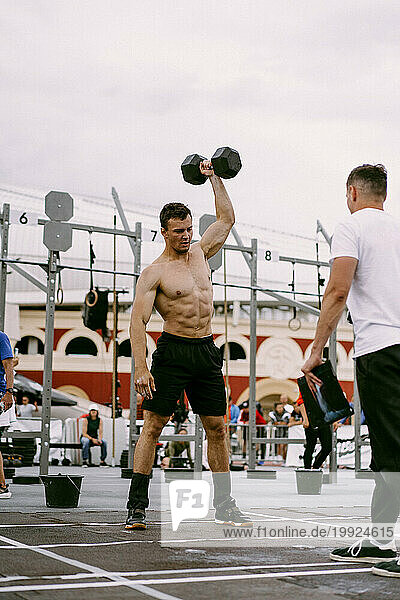 Men's CrossFit competition. A man lifts a dumbbell.