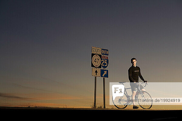 A man stops by a road sign while riding his bike in Albuquerque  New Mexico.