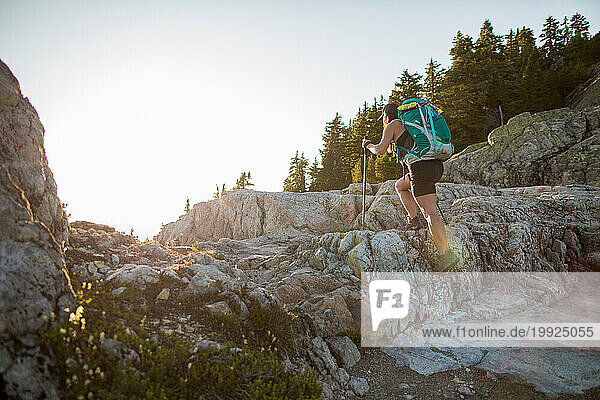 Side view of fit female backpacker hiking over talus rock