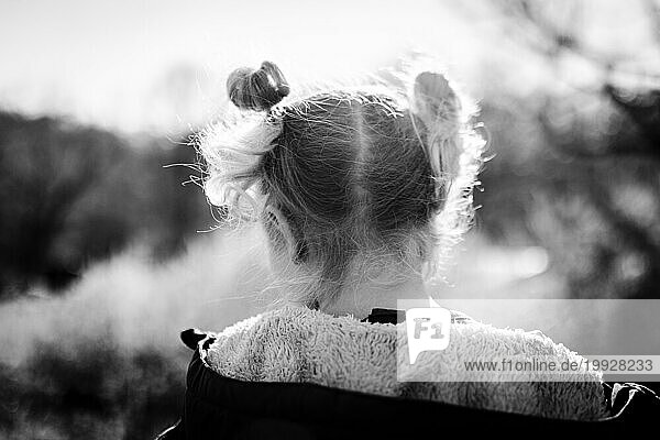 Back view close up of child with pigtails on windy day