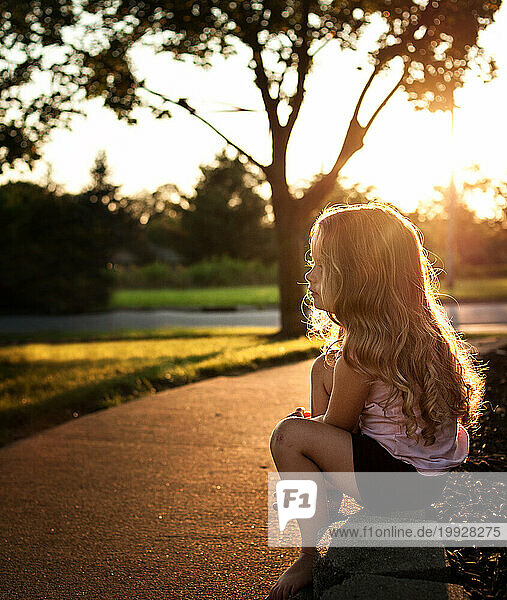 Beautiful little girl with long curls outdoors in summer