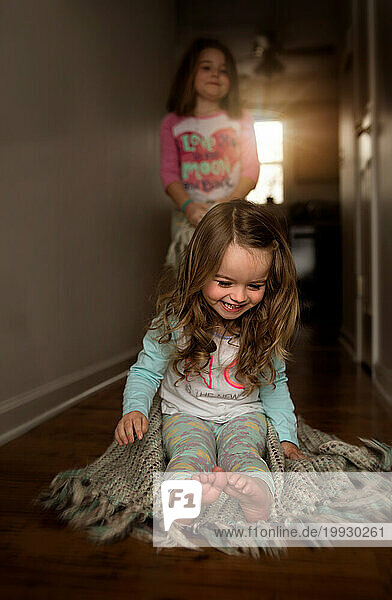 Young sisters playing and laughing in hallway of home