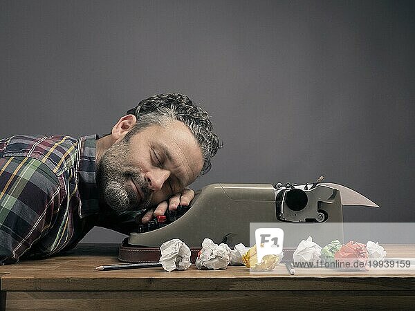 Zerknittertes Papier mit einer alten Schreibmaschine auf einem hölzernen Bürotisch  Businessmann schläft  Kreativität Konzept