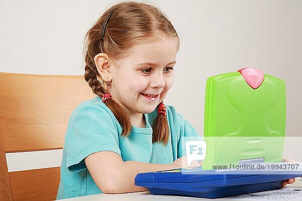 Niedliches kleines Mädchen macht Hausaufgaben mit ihrem Computer