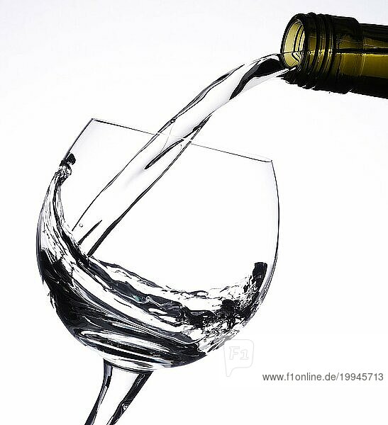 Einschenken von Weißwein in ein Glas vor einem hellen Hintergrund  kontrastreiche Studioaufnahme