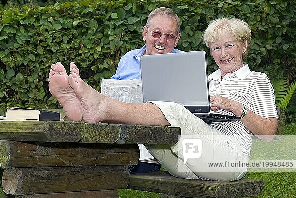 Seniorenpaar im Garten mit Laptop