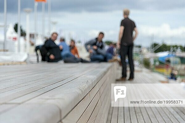 Eine Menschengruppe sitzt auf Holzbänken am Strand von Travemünde