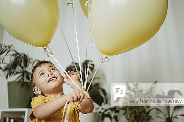 Happy boy playing with balloons at home