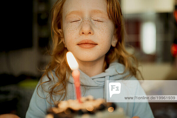 Girl holding birthday cake with candle at home
