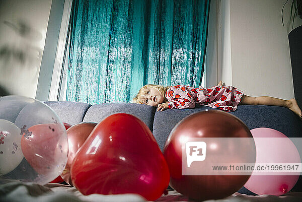 Girl lying on sofa with balloons at home