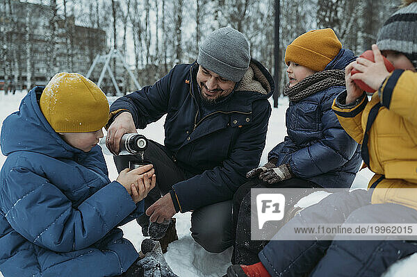 Happy family having tea in winter park
