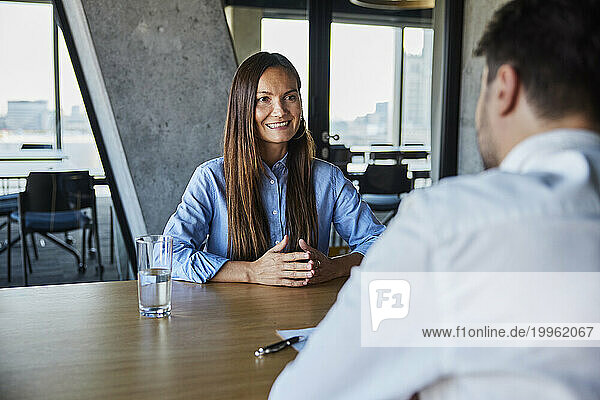 Smiling businesswoman sitting and talking to candidate in office