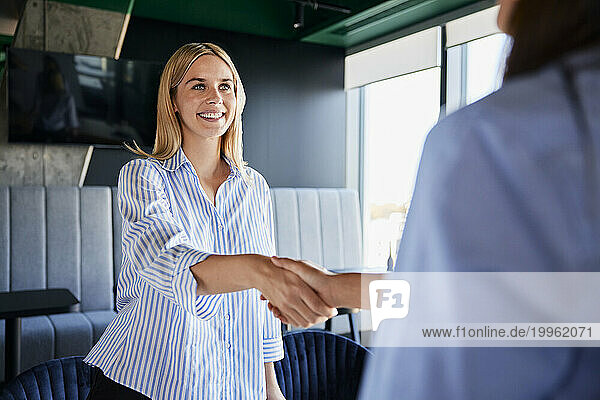 Smiling recruiter shaking hands with candidate at office