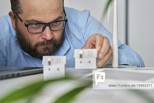 Architect examining house models at desk in office