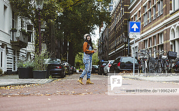 Woman walking on street near cars and bicycles in front of buildings