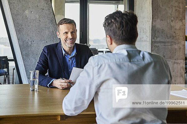 Happy recruiter taking interview of candidate at desk