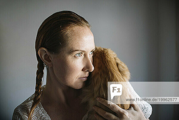 Redhead woman embracing cat at home
