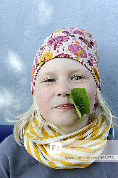 Portrait of little girl with leaf in mouth