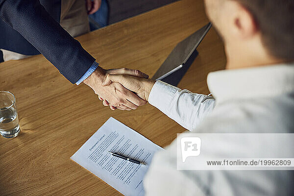 Recruiter shaking hands with candidate at desk