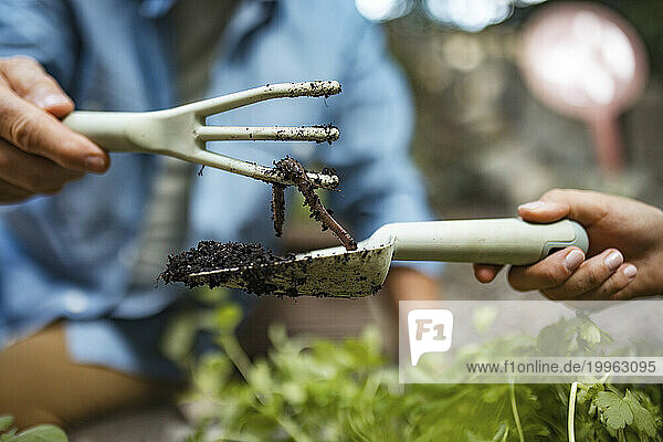 Gardener saving an earthworm with a hand rake