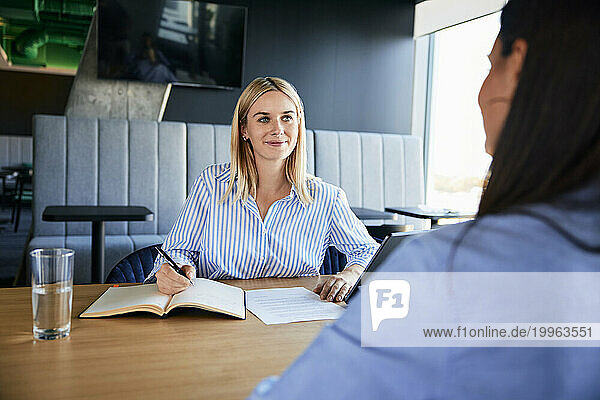 Smiling recruiter taking interview of candidate at desk