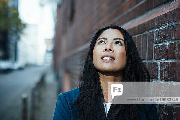 Contemplative businesswoman near brick wall