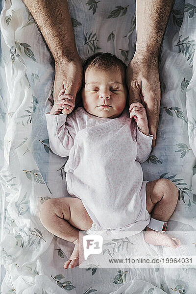Hands of father holding sleeping baby girl