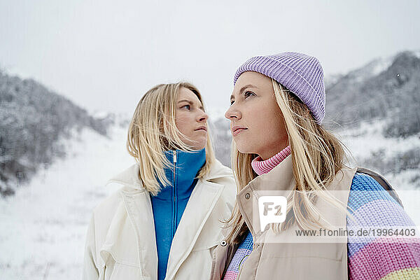 Thoughtful friends on snowcapped mountain