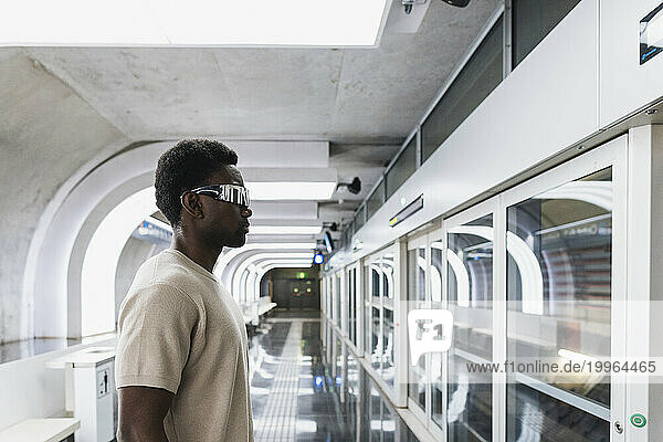 Man wearing futuristic glasses standing at metro station