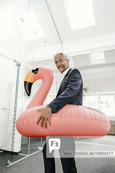 Businessman in office with inflatable flamingo