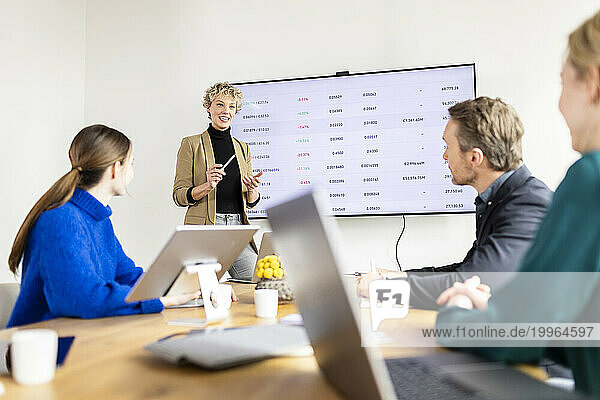 Businesswoman giving presentation to colleagues in meeting at office