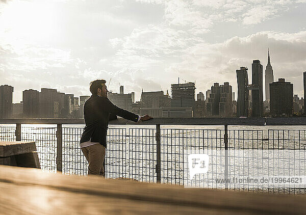 Businessman leaning on railing near Hudson river in New York City  USA