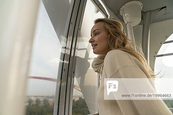 Blond woman looking through Ferris wheel window