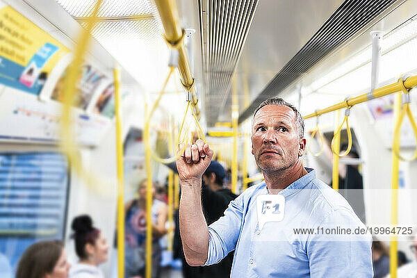 Businessman holding handgrip and commuting through train