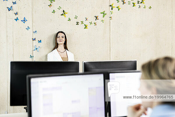 Thoughtful young trainee standing in front of wall at workplace