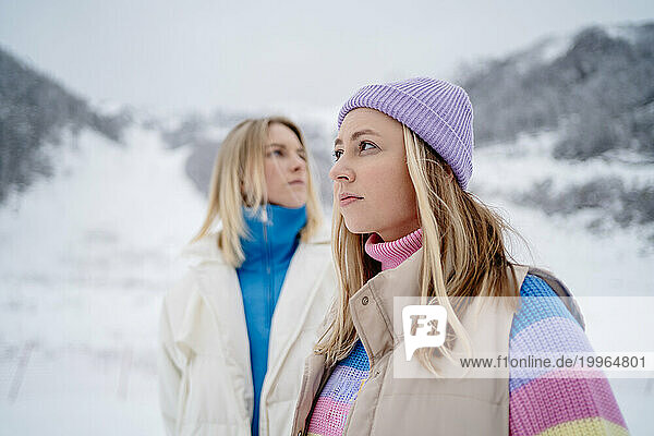 Contemplative friends standing at ski resort