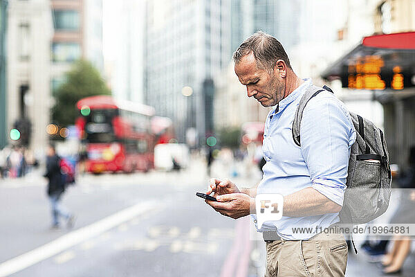 Businessman using smart phone on street